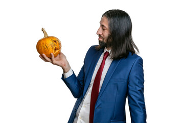 A man with a beard and long hair in a jacket and shirt with a  Halloween pumpkin in his hands posing on a white background. Various poses and emotions. Halloween concept. 