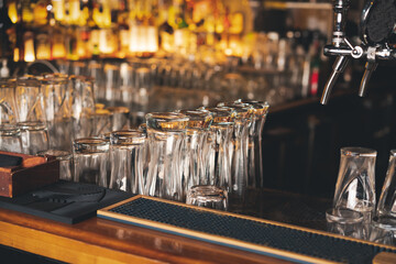 Fototapeta na wymiar Bar counter in a bar, glasses and tap for draft beer