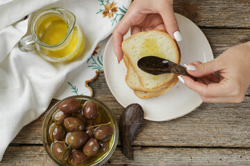 Woman having healthy snack, olives, olive oil and bread.
