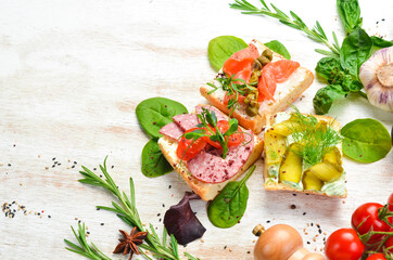 Set of sandwiches with vegetables and salmon on a wooden board. Top view. Rustic style.