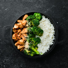 Healthy food. Chicken with teriyaki sauce, boiled rice and broccoli in a black pan. Rustic style....