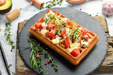 Belgian waffles: with bacon, tomatoes and microgreens. Breakfast. On a black stone plate.