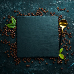 Fragrant roasted coffee beans on a black stone background. Top view. Free space for text.