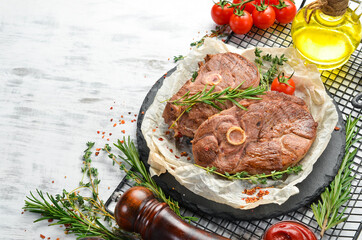 Barbecue. Lamb steak with spices and vegetables on a white wooden background. Flat lay. Top view.