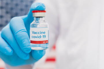 Doctor holding vaccine bottle with USA flag background.