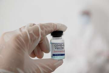 Doctor Hands in protective gloves holding Coronavirus 2019-nCoV Vaccine vial.