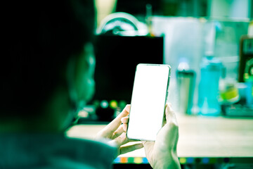 Mockup image blank white screen smart phone, man hand holding using mobile phone at office, concept of lifestyle in coronavirus situation, copy space on smart phone for advertisement