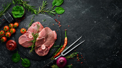 Meat. Lamb steak on the bone with rosemary and spices. On a black stone background. Top view.