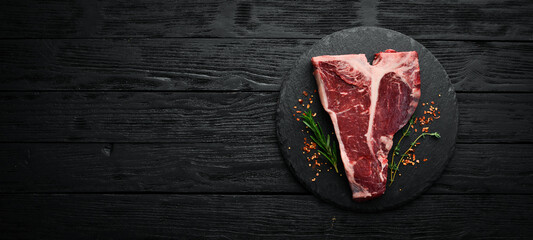 Raw T-bone steak on a stone table with thyme, rosemary and spices. Top view. Flat lay top view on...