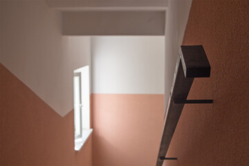 A blurred black metal handrail on the right, along a beige-painted wall descending to the lower...