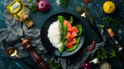 Rice with red fish, green beans and spinach in a black plate. Diet. Top view. Free space for text.