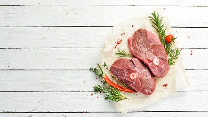 Meat. Raw boneless lamb steak with rosemary and spices. On a white wooden background. Top view.