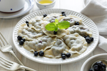 Dumplings with blueberries on a white plate, close up view. Traditional dish in Poland