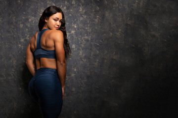Fototapeta premium young and beautiful Hispanic bodybuilder athlete posing on her back in blue sportswear