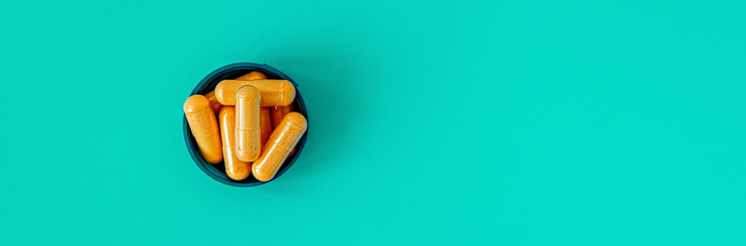 b-complex multivitamin supplement capsules on turquoise background. dietary supplement top view banner. mental wellbeing and personal health concept copy space