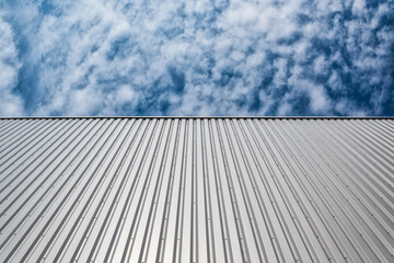 View upwards to the facade of a warehouse with a cladding of silver corrugated aluminum sheet.