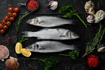 Sea bass fish with spices and herbs. Preparation. On a dark kitchen background. Top view.