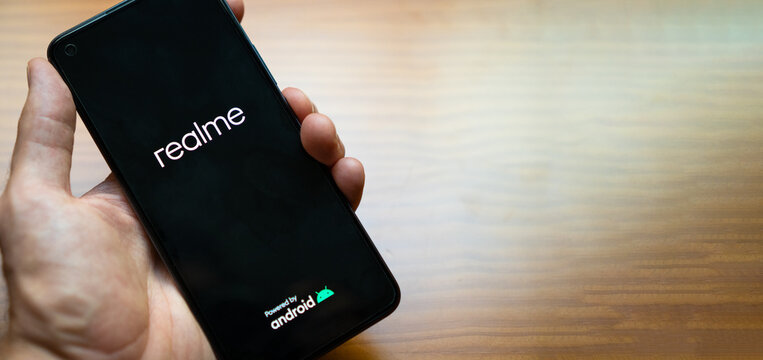 Madrid, Spain - July 25, 2021: Hand of a person holding the new smartphone Realme 8 while turning on. New android mobile phone, copy space right.