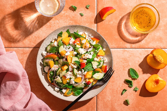 Summer peach and cheese salad on tile table, top view