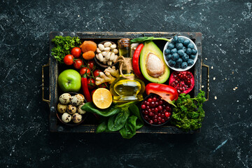 Set of healthy food in a wooden box: vegetables, fruits, fish, meat, nuts and herbs. Top view. Free copy space.