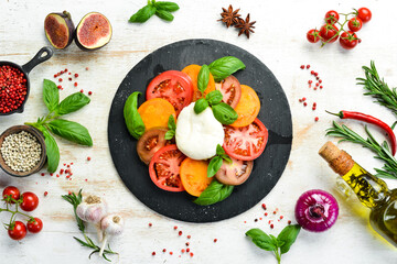 Caprese salad with fresh tomatoes, mozzarella cheese and basil. Italian food. Top view.