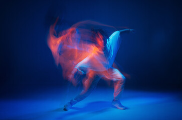 Mixed race young girl dancing in colorful neon studio light. Long exposure. Contemporary hip hop...