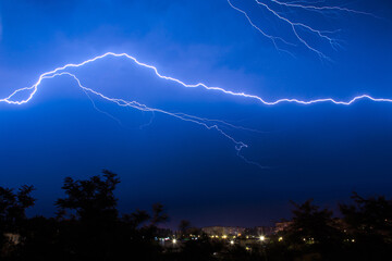 Lightning discharges during a large rainstorm in a city with forest fringes