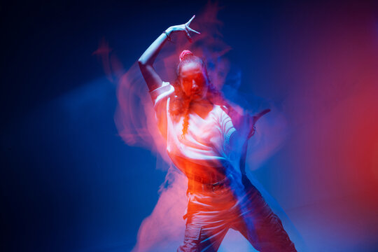 Cool mixed race young girl moving in colourful studio light. Long exposure. Contemporary stylish advertising photo