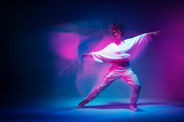 Mixed race female dancing in colorful neon light. Studio photo with long exposure. Expressive...