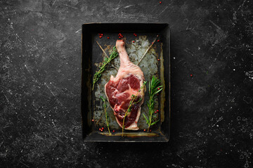 Poultry meat. Fresh raw duck thigh with rosemary and spices. On a black stone background. Top view.