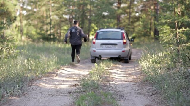 a man is standing in the middle of the forest, his car has broken down, he is trying to pass, but there is no connection.