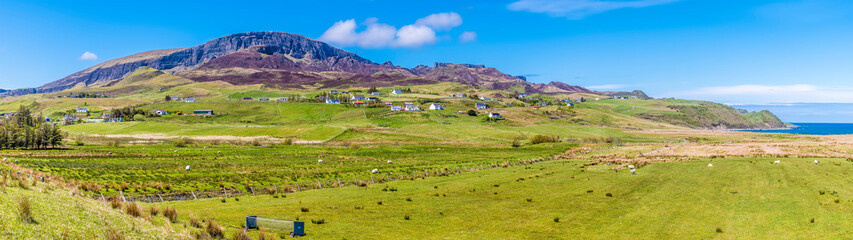 Fototapeta na wymiar A panorama view across Staffin Bay towards the Quiraing Mountains in the distance on the Isle of Skye, Scotland on a summers day