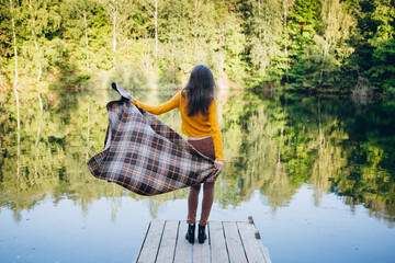 Fototapeta na wymiar Woman stands on a bridge on a lake with an autumn landscape