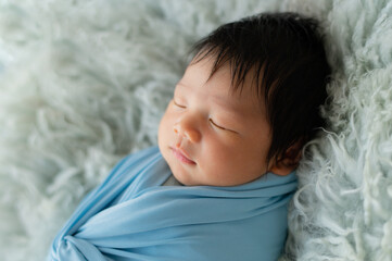 Cute  baby with blue sky  wrap lying on the  blanket.