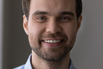 Obraz premium Close up cropped portrait of handsome young bearded guy face. Attractive millennial caucasian man successful businessman motivated worker looking at camera with perfect white toothy smile in good mood