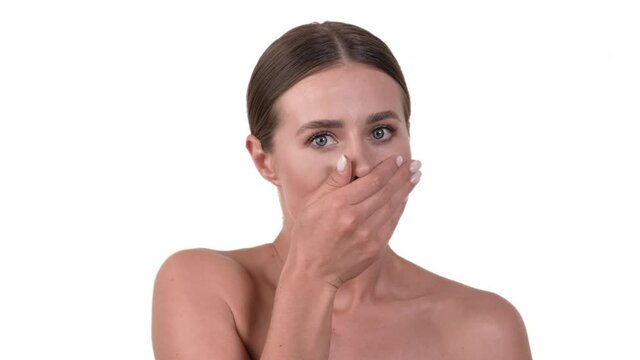 Portrait of surprised woman, covering her mouth with her hand. White background.
