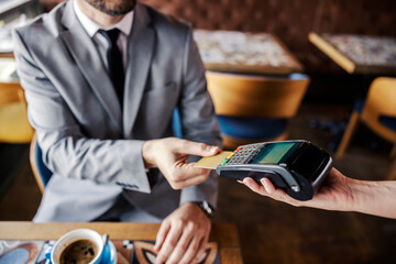 Online card payment in the restaurant. A man in a business suit with a tie sits at a table in a...