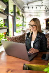 Young woman sitting at cafe with laptop