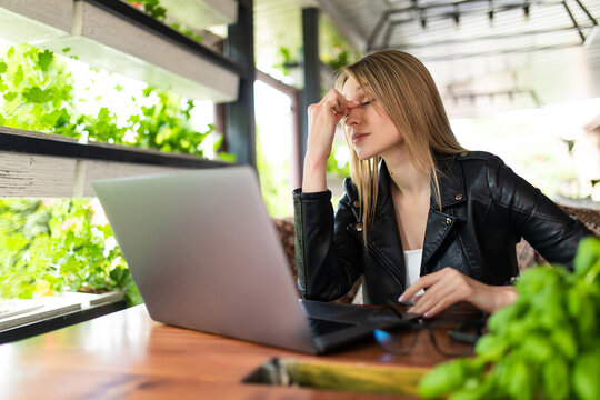 Freelance woman headache tired, stess or deadline with digital laptop working on workplace in coffee shop.