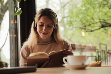 Woman listening to audiobook at table in cafe