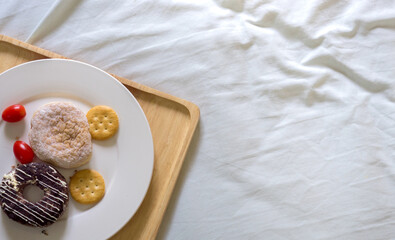 Tray With Breakfast On Bed.Wooden tray with served breakfast lying on bed blanket with opened book.