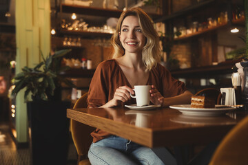 Young woman with cup of coffee at cafe in morning
