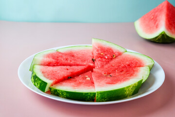 Pieces of watermelon on a round plate on a pink background. Top view, flat lay.
Ripe watermelon slices.
Vegetarian food.
Place for text