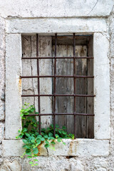 Window with rusty bars on the old stone wall.