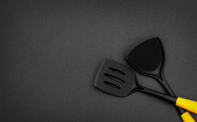 Two plastic spades of frying pan on black. Top view. Space for text.
