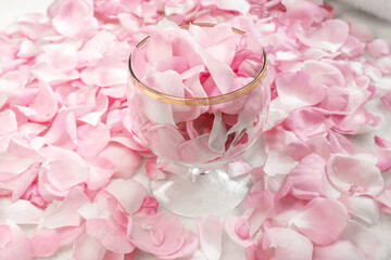 A transparent wine glass filled with pink rose petals.