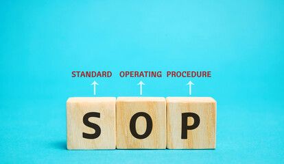 Wooden blocks with the word SOP ( Standard operating procedure ). Instructions to assist employees...