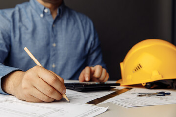 Construction concept. Engineer's workplace with yellow helmet, calculator and drawing tools