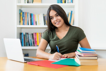 Pretty spanish female student learning at desk