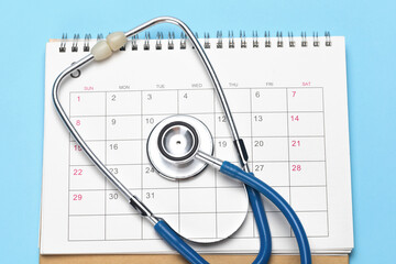 Calendar and stethoscope on a blue background. The concept of a planned examination by a doctor